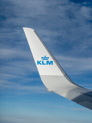 Obraz premium Winglet of a KLM Royal Dutch Airlines airplane flying high in the blue sky, view from the window