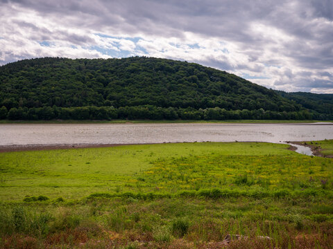 Low water level at Doma&scaron;a reservoir during drought. Exposed lakebed covered with grass and a small inflow near Petejovce, showing the effects of dry weather.