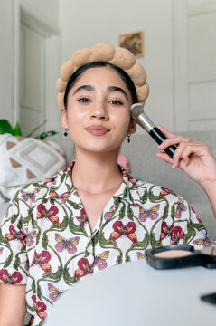 Teenager applying face powder with makeup brush