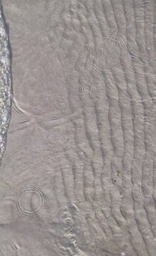 Top view of clear sea water lapping on a baltic shallow sand shore