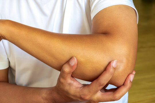 Hand supporting elbow in white shirt, symbolizing modern healthcare solutions, recovery support, and professional medical care.
