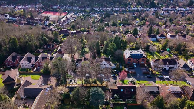 Leafy residential neighbourhood with detached homes, gardens and suburban streets in Croydon, Greater London, England, cinematic panning aerial view