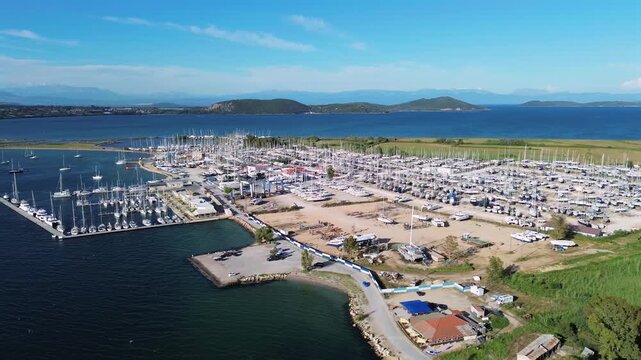 A horizontal drone high angle shot showcasing the massive infrastructure and organized layout of a modern commercial dry dock facility with hundreds of yachts parked for winter storage in Greece.