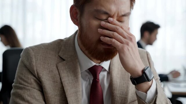 Stressed Red-Haired Businessman Covering Face in Office, Feeling Overwhelmed and Exhausted
