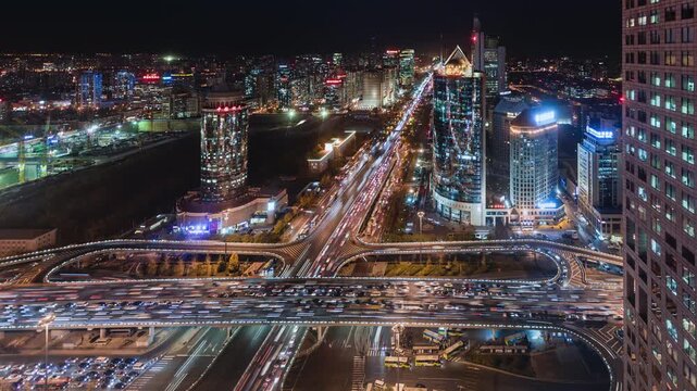 High angle view time Lapse at night of busy road intersection in Beijing's financial district with traffic and commuters at rush hour