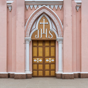Pink facade and arched golden entrance with JHS symbol at Da Nang Cathedral, also known as Sacred Heart Cathedral in Da Nang, Vietnam