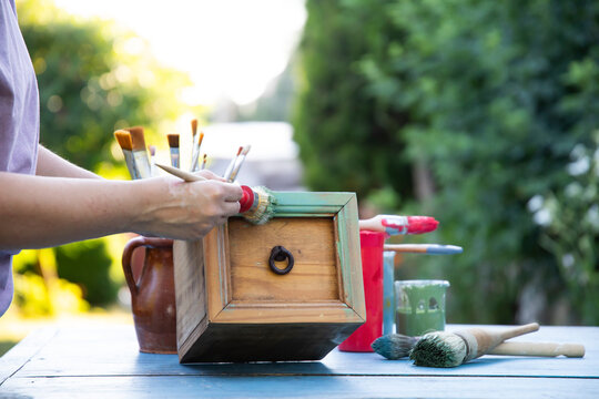 Painting a wooden furniture outdoors, an eco-friendly re-use business.