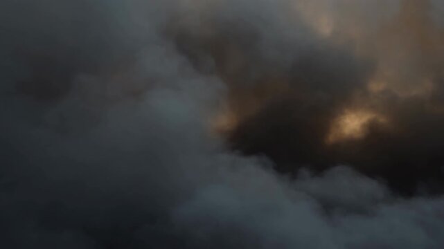 Wide panoramic smoke billowing upward and thinning to reveal warm ember glow through cool mist, with layered haze, swirling motion, dark contrast, and moody atmospheric texture