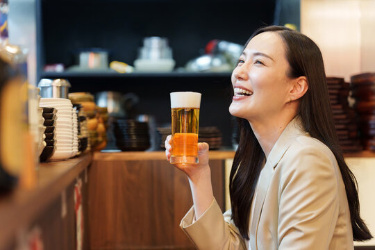 居酒屋で生ビールを飲むビジネスウーマン
