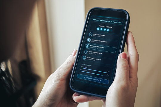 Close-up of a person holding a smartphone displaying a futuristic service excellence evaluation dashboard, monitoring customer feedback, performance metrics, and digital data security analytics.
