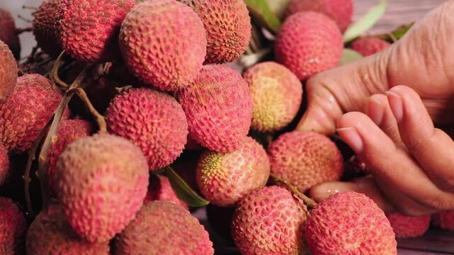 Picking sweet lychee from a colorful pile of fruit