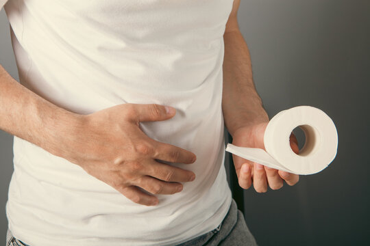 Man holding toilet paper roll on grey background. Close-up.