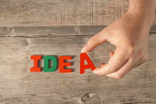 Man building word Idea with wooden letters on table, close-up