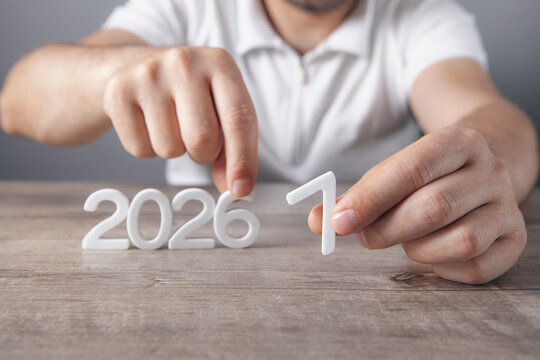 Top view of male hands holding wooden number 2027 over wooden table. New year concept
