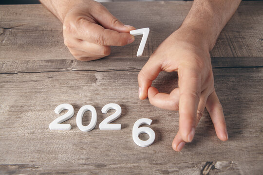 Top view of male hands holding wooden number 2027 over wooden table. New year concept