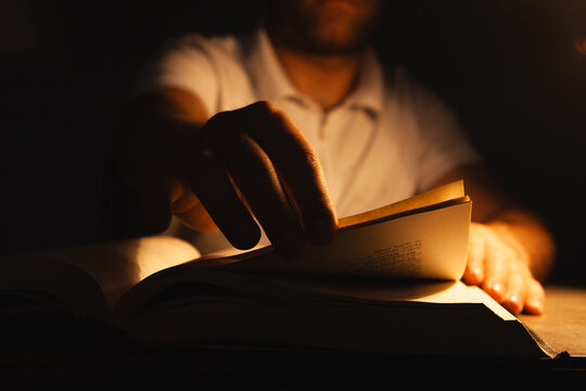 Man reading a book in the dark at night.
