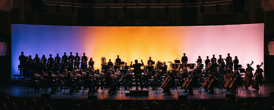 Silhouette of a full symphony orchestra and choir performing on stage with a colorful gradient background