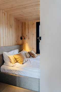 Vertical shot of cozy wooden bedroom with soft pillows inside modern tiny house