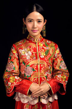Asian Chinese girl wearing ancient costume and red makeup against a black background