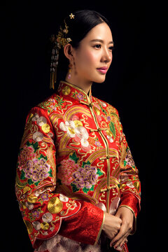 Asian Chinese girl wearing ancient costume and red makeup against a black background