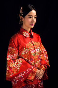 Asian Chinese girl wearing ancient costume and red makeup against a black background