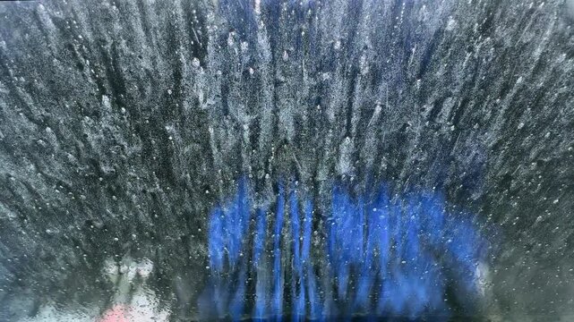 A drive through car was operating with it's jets of water and rotating brushes seen through the from window of a car, Worcestershire, England.