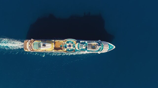 Top down drone backdrop of cruise ship sailing across deep blue open sea leaving wake, aerial vacation texture with large long shadow
