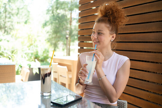Young woman drinking lemonade in a cafe outdoor on a sunny summer day