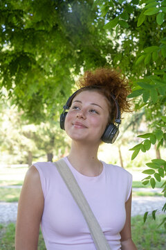 Young woman portrait listening to music on headphones in the park