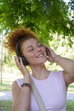 Young woman portrait listening to music on headphones in the park