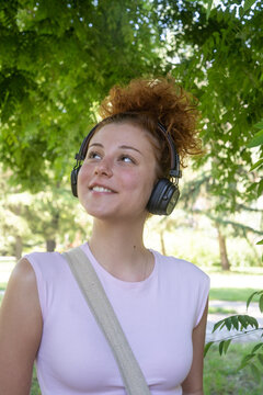 Young woman portrait listening to music on headphones in the park