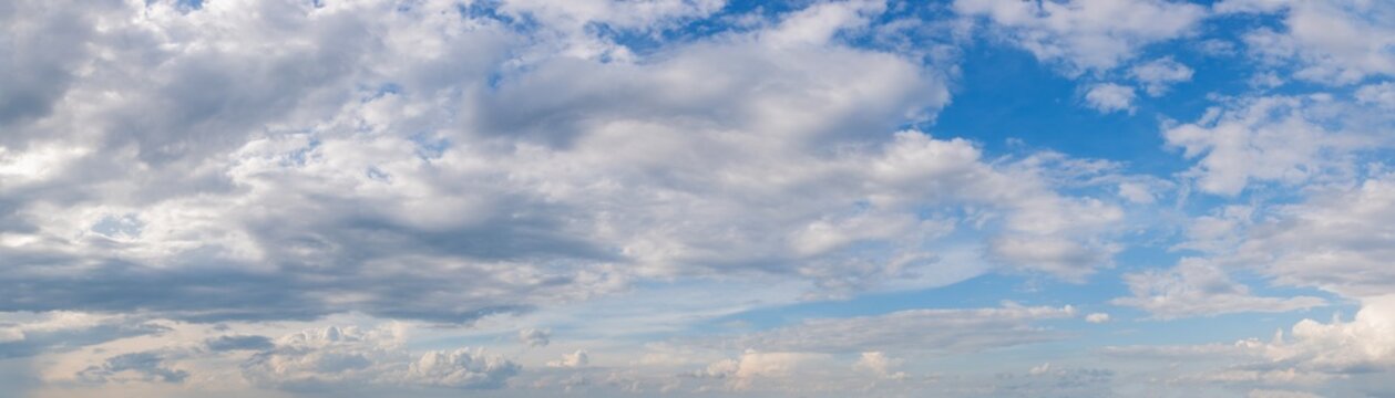 Wide angle panorama of beautiful sky with cumulus clouds  over a clear horizon.