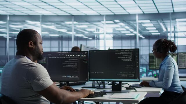IT specialist shields valuable data in server farm involving server hub from a secondary camera angle while connecting protected data, access control and server room reliability.