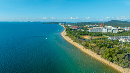 Fototapeta premium Aerial view of colorful mediterranean buildings along grand canal with pedestrian bridge. Grand world Phu Quoc with vibrant cafes, shops and blooming trees.