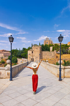 Rear view of young woman tourist with open arms celebrating on San Martin bridge in medieval city of Toledo, Tour tourism, travel destination in Spain