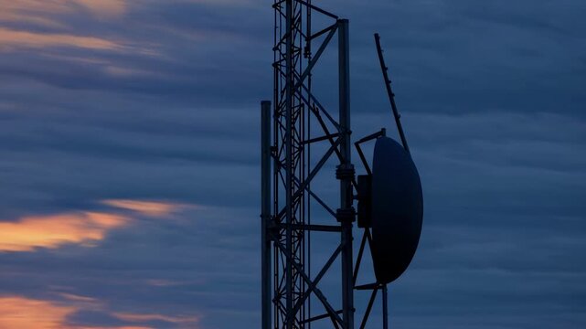 Communication tower silhouette against a vibrant sunset sky, showcasing the structure's details and the changing colors of the evening atmosphere