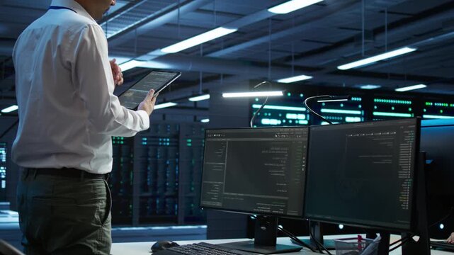 IT professional provides technical support in a high tech server room with a tablet, balancing network security, data protection and database reliability inside active data center oversight