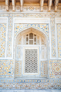 Elegant close-up of an intricately carved marble jali window framed by colorful pietra dura floral inlays and geometric Mughal motifs at the Itmad-ud-Daulah Tomb, known as the Baby Taj, in Agra, India