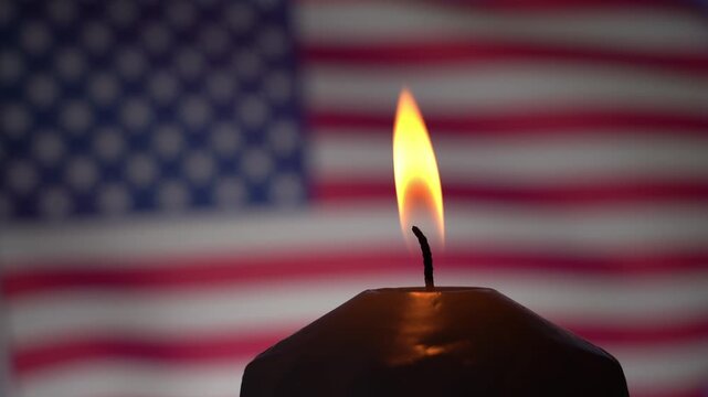 Lit candle on the background of the American flag. Mourning for fallen American soldiers during the confrontation.