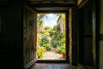 Fototapeta premium Doorway framing bright exterior garden view from dark interior