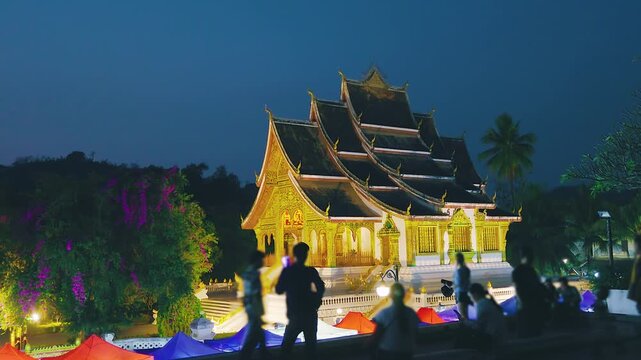 Majestic illuminated temple at night with visitors enjoying the cultural heritage site Luang Prabang Laos
