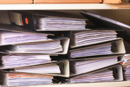 Operational compliance review documents stacked in office binders showing organized paperwork and administrative process