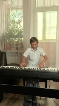 Teen Boy Playing Digital Piano At Home