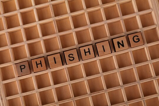 Close-up of wooden Scrabble tiles spelling phishing on a grid background