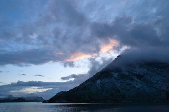 Dramatic clouds over mountains and fjord at twilight
