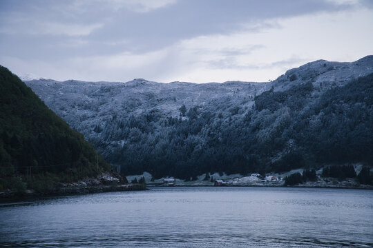 Snow-covered mountain slopes and small huts by a Nordic fjord