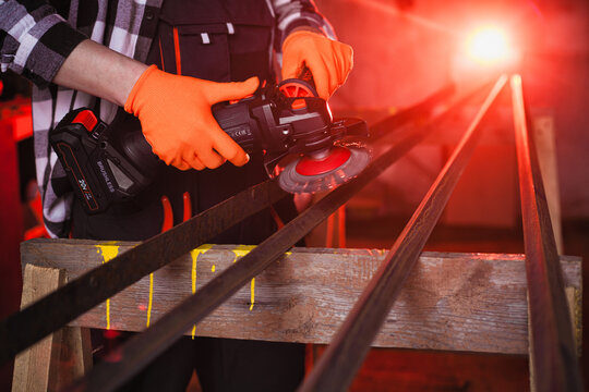 A man cleans metal using an angle grinder. Many sparks