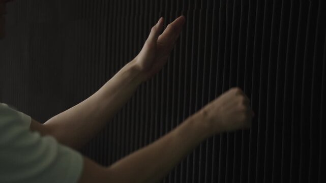 Sound engineer clapping hands to test acoustic foam paneling for absorption, echo, reverberation reduction in dark professional recording music studio, close-up. Shooting in slow motion.