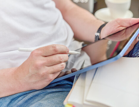 Close-up of student writing notes in digital tablet screen  while sitting on sofa at home, study and education concept for homework, exam preparation, remote learning, planning, productivity