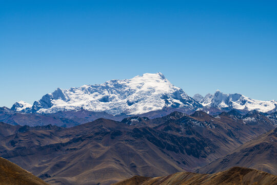 The massive snow-capped peaks and bright white glaciers of Mount Ausangate rising above the rugged Andes range in Peru